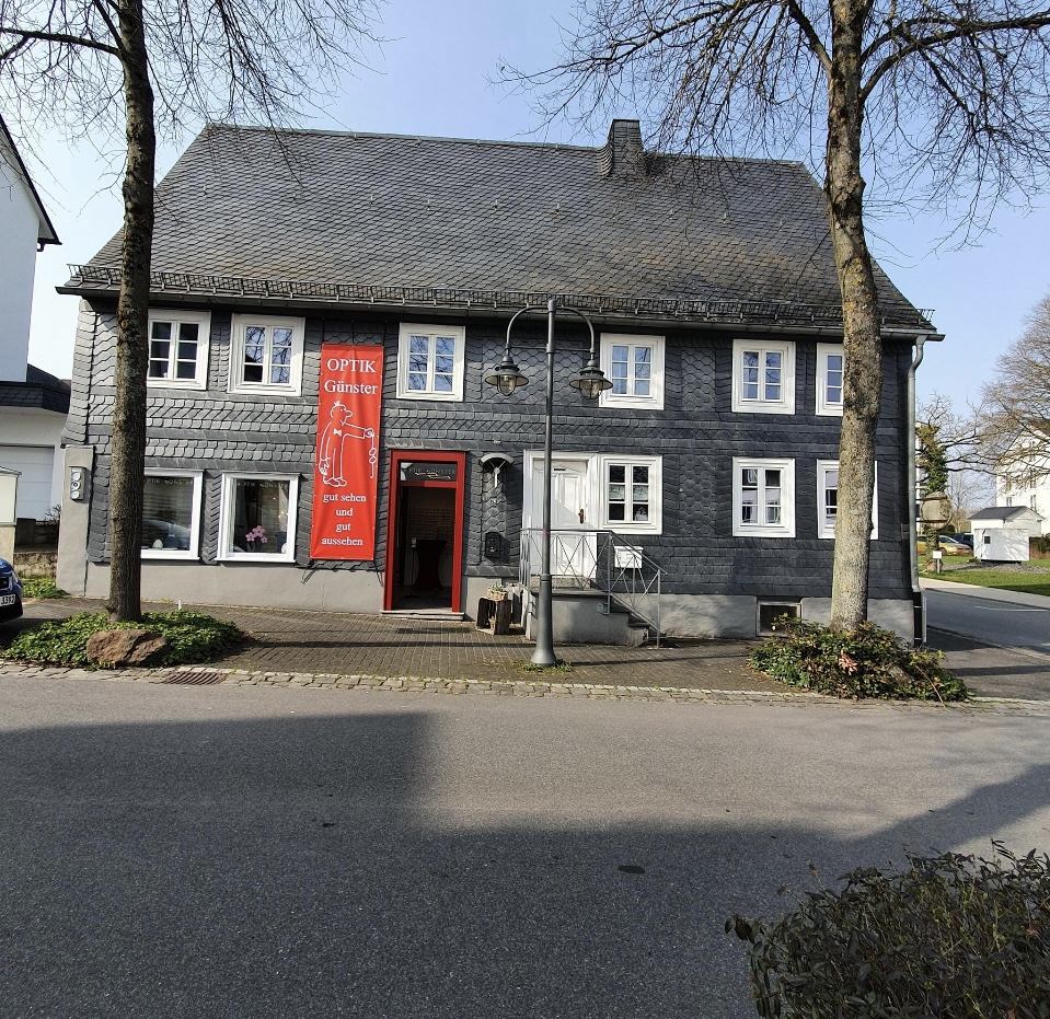 Schiefergedecktes Geschäftshaus von Optik Günster in Brilon mit rotem Banner